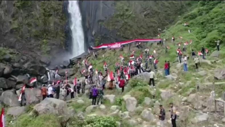 Personel Gabungan di Asahan Kibarkan 75 Bendera Merah Putih di Bawah Air Terjun Ponot