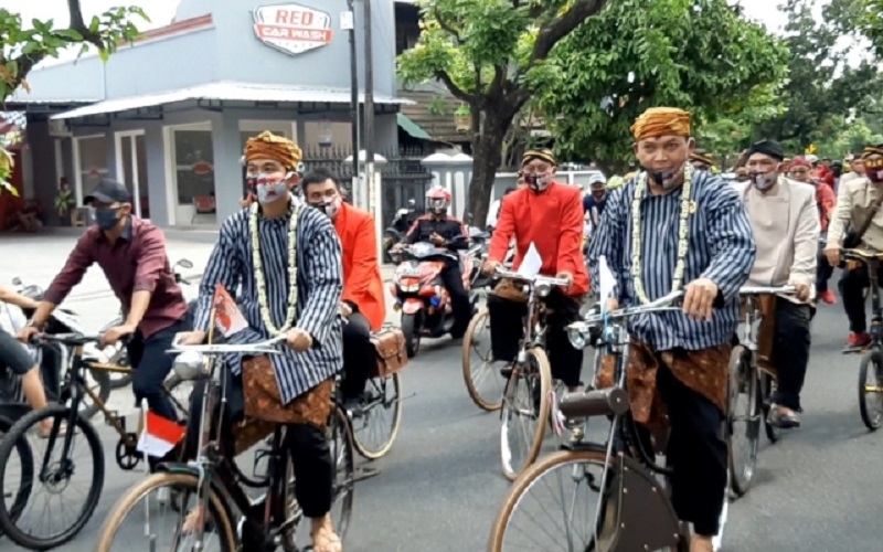 Pakai Baju Lurik Berkalung Melati, Gibran-Teguh Gowes Bareng ke KPU Solo