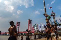 Potret Lomba Panjat Pinang Dipinggir Sungai Musi