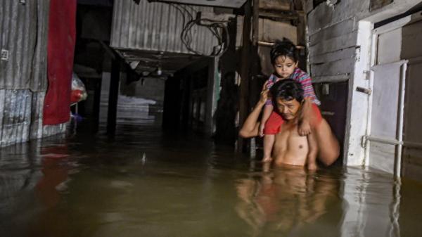 banjir jakarta ant Seorang warga memanggul anaknya melewati banjir di kawasan Kampung Baru, Kembangan, Jakarta Barat, Kamis (2/1/2020). Banjir di wilayah ini mulai surut, meski belum sepenuhnya kering, Jumat (3/1/2020). (Foto: Antara/Muhammad Adimaja).