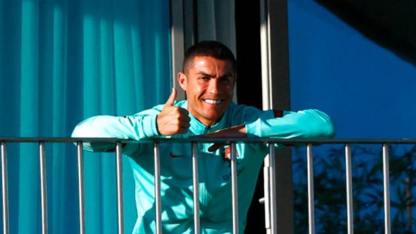 Cristiano Ronaldo menyapa dari balkon hotel Timnas Portugal, tempat dia melakukan isolasi, Rabu (14/10/2020). (Foto: The Sun)