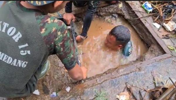 TNI Anggota Satgas Subsektor 15 Citarum Harum, Serka Erik Krisyana menyelam di selokan, Jalan Raya Parakan Muncang, Kecamatan Cimanggung, Sumedang. (Foto iNews/Beben HVA).
