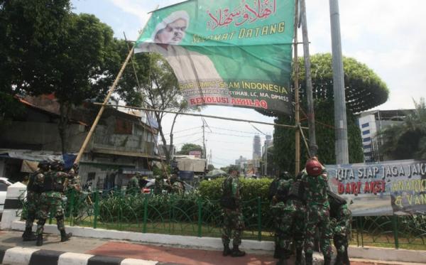 Prajurit TNI dan personel gabungan menurunkan baliho bergambar Habib Rizieq Shihab di kawasan Petamburan, Jakarta, Jumat (20/11/2020) karena dianggap menyalahi izin. (Foto: SINDOnews/Eko Purwanto)