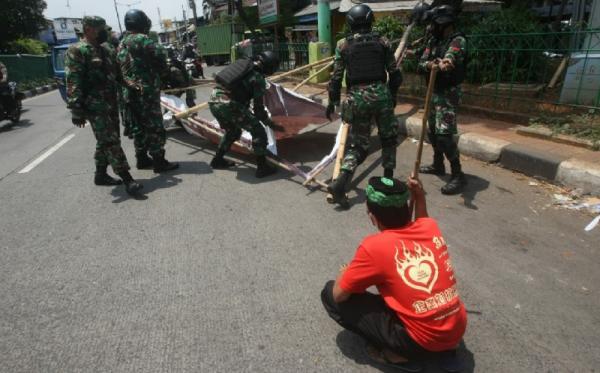 Prajurit TNI dan personel gabungan menurunkan baliho bergambar Habib Rizieq Shihab di kawasan Petamburan, Jakarta, Jumat (20/11/2020) karena dianggap menyalahi izin. (Foto: SINDOnews/Eko Purwanto)