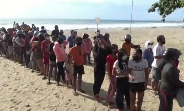 Ratusan warga mengantre di Pantai Legian, Bali untuk mendapatkan makanan gratis. (iNews.id/Bagus Alit)