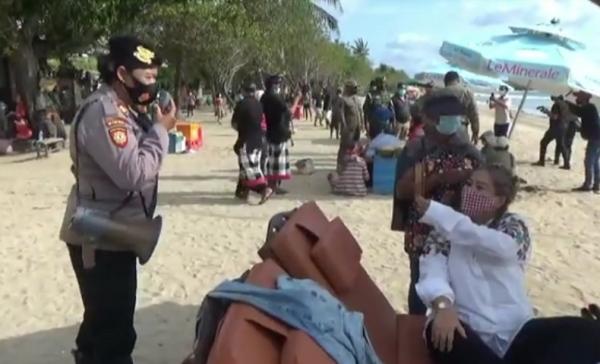 Petugas kepolisian memberi peringatan kepada wisatawan yang belum menerapkan protokol kesehatan. (iNews.id/Bagus Alit)