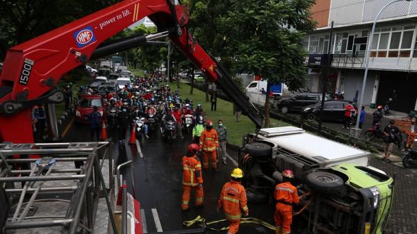 truk terguling di surabaya2 Petugas Damkar mengevakuasi sebuah truk yang terguling di Jalan Ir Soekarno Hatta (Merr), Surabaya, Jawa Timur, Kamis (25/2/2021). (Foto: SINDONews/Ali Masduki)