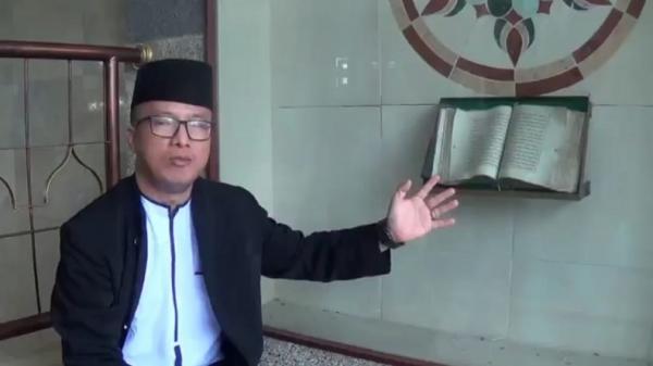 Sekretaris DKM Dedy Priatna menunjukkan Alquran tua tulisan tangan peninggalan KH Abdurrohim atau Mama Aden pendiri Masjid Mungsolkanas. (Foto: iNews/Ervan David)