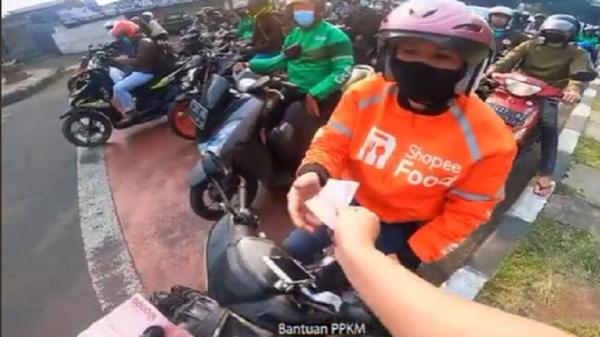 Pemotor asal Jombang Ahyar Wahyu R membagikan uang Rp100.000 ke setiap pengendara sepeda motor di lampu merah. (Foto: tangkapan layar TikTok)