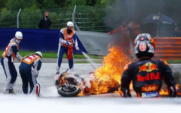 Pembalap Red Bull KTM Factory, Dani Pedrosa, menyaksikan motornya terbakar di Seri Styria, Spielber, Austria, pada Minggu (8/8/2021). (Foto: REUTERS/Borut Zivulovic)