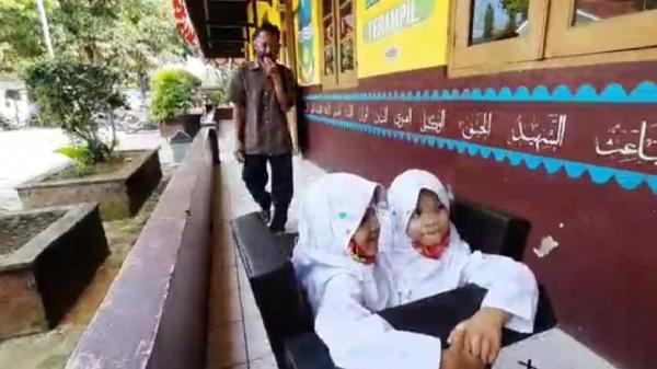 KEMBAR SIAM Iwan Kurniawan mengantarkan kedua putrinya, Al Putri Dewi dan Al Putri Anugrah ke sekolah. (Foto: iNews/Ii Solihin)