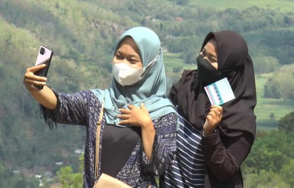 Waga berselfie di spot foto Kebun Buah Mangunan, Bantul sambil menunjukkan kartu vaksin. (foto: iNews.id/Trisna Purwoko)