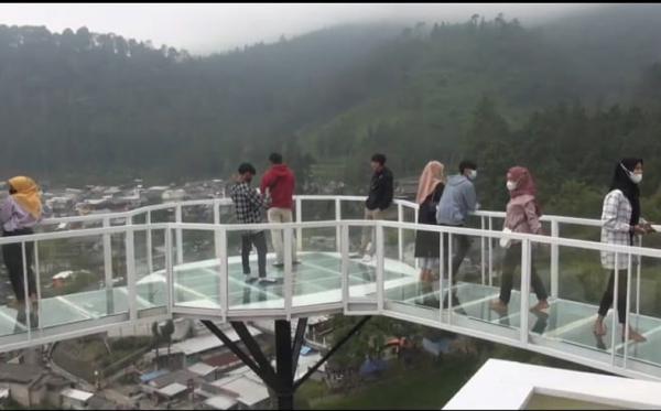 jembatan kaca guci Sejumlah pengunjung saat menikmati pemandangan alam dari atas jembatan kaca di wahana Baron Hill kawasan wisata Guci Tegal. (iNews/Yunibar)