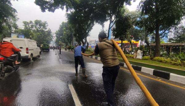 Petugas Damkar Bogor membersihkan jalan yang terkena tumpahan solar truk. (Foto damkar Bogor).