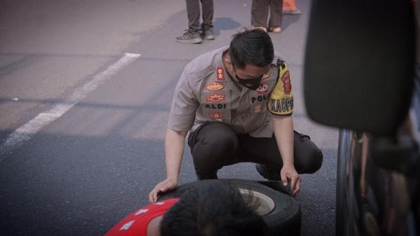 BAN BOCOR Kapolres Karawang AKBP Aldi Subartono saat mengganti ban mobil pemudik yang bocor di Km 57 Tol Japek. (FOTO: Humas Polda Jabar)