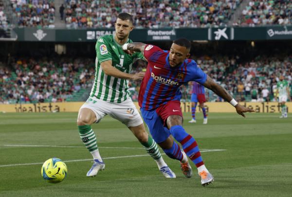 Penyerang Barcelona, Memphis Depay Penyerang Barcelona, Memphis Depay dikawal ketat pemain Real Betis, Guido Rodriguez dalam laga Liga Spanyol 2021/2022 di Stadion Benito Villamarin, Minggu (8/5/2022). (Foto: REUTERS)