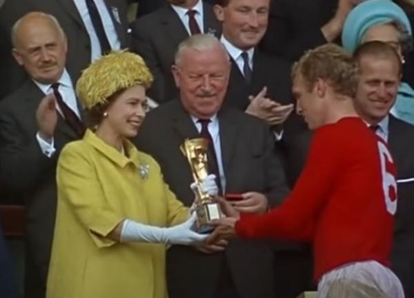 Ratu Elizabeth Inggris Piala Dunia 1966 Ratu Elizabeth tampak semringah saat menyerahkan trofi Piala Dunia Jules Rimet kepada kapten Timnas Inggris, Bobby Moore. Pada laga final edisi 1966 itu, Inggris menang 4-2 atas Jerman Barat di final. (Foto: Tangkapan layar YouTube/Sporting History)