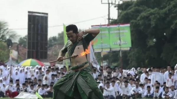 Seorang pria anggota Pagar Nusa melakukan atraksi kebal api untuk memeriahkan HPN 2022. (FOTO: iNews/M ZENI JOHADI)