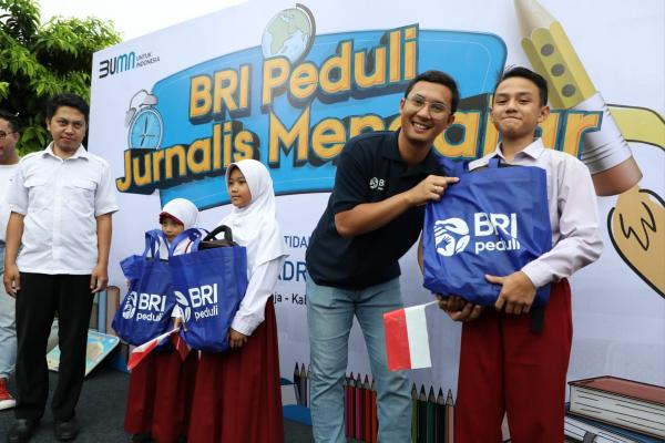 Jurnalis BRI Mengajar Senior Manager CSR BRI, M Ganjar Nugraha, menyerahkan bantuan peralatan sekolah kepada salah satu murid MI al-Badriyah Gunung Geulis, Bogor, Sabtu (28/1/2023). (Foto: Dok. BRI)