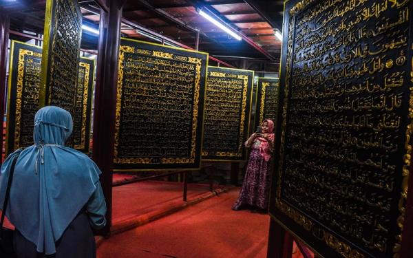 Al Quran terbesar di dunia Pengunjung berada di antara lembaran Al Quran terbesar di dunia di Palembang. (Foto: Sindonews)