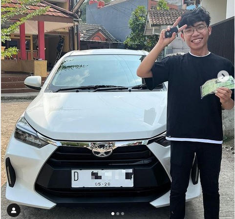 Febbry Flash Sale Rp1 Agya Febbry bersama mobil dan menunjukan STNK miliknya.