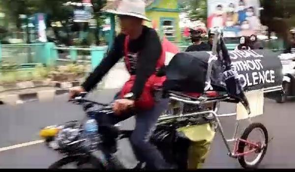 Miftahudin bersepeda sambil membawa keranda menuju Jakarta. (Avirista Midaada).