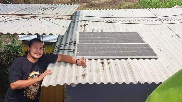 Khilmi Panel Surya Khilmi Sabihisma mengecek panel surya yang terpasang di atap warung kopi.