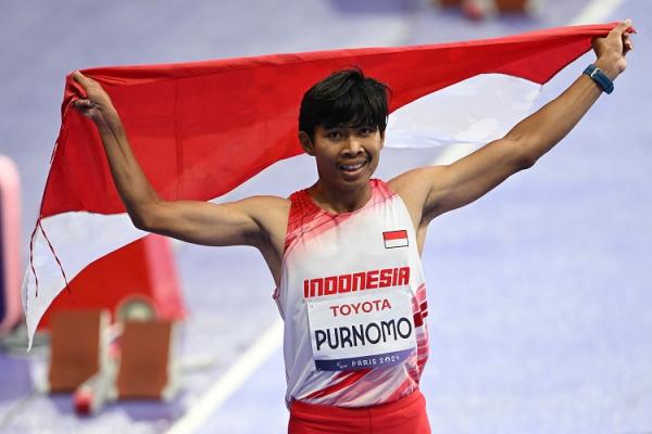 Atlet para atletik Indonesia, Saptoyogo Purnomo, mengibarkan Merah-Putih usai meraih medali perak Paralimpiade Paris 2024, Sabtu (31/8/2024) dini hari WIB. (Foto: NOC Indonesia)