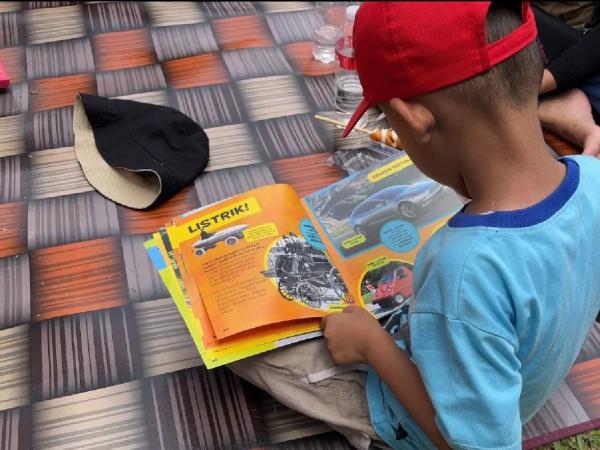 Anak membaca buku Salah satu sudut di acara Lebaran Betawi 2026 di Lapangan Banteng, Jakarta Pusat, Minggu (12/4/2026). (Foto: Niko Prayoga)