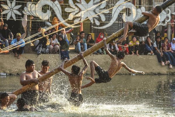 Potret Lomba Panjat Pinang Miring di Kolam Retensi